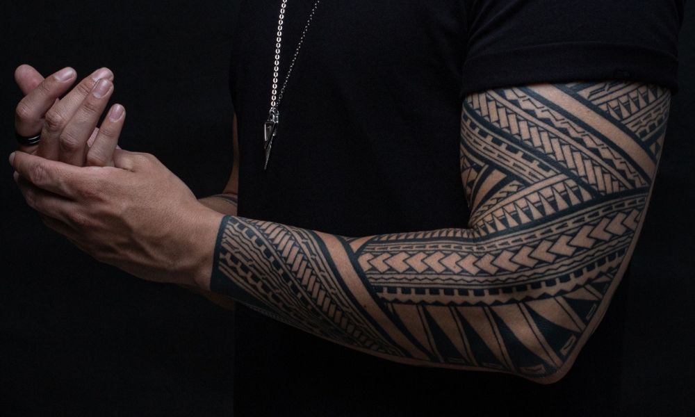 Tattooed arm with intricate tribal designs, showcasing aftercare importance for new tattoos.