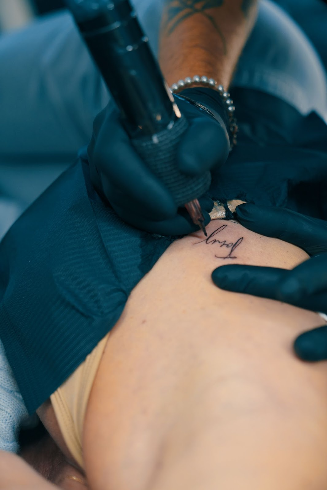 Close-up of artist in the process of tattooing a fine-line script tattoo on a client's ribs