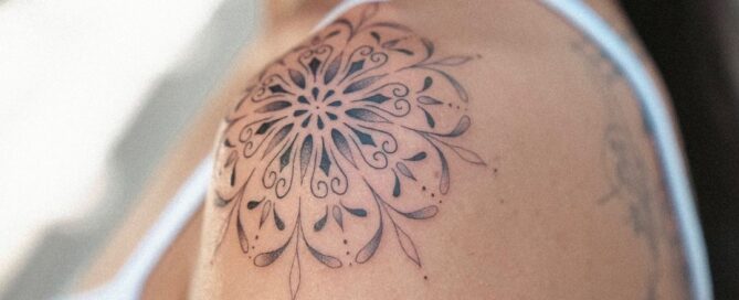 Black and grey ornamental mandala tattoo placed on the shoulder cap.
