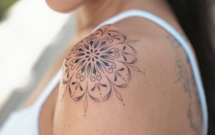 Black and grey ornamental mandala tattoo placed on the shoulder cap.