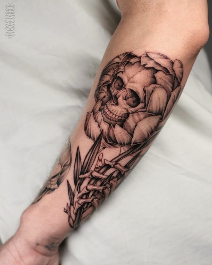 Skull tattoo surrounded by floral elements on a forearm, showcasing fine line details and shading, emphasizing the importance of tattoo maintenance and touch-ups.