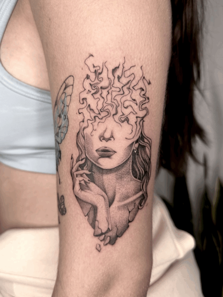Black and grey surrealist tattoo of a woman with fragmented shoulders and swirling smoke patterns where her forehead would be