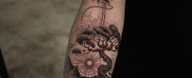 Black and grey forearm tattoo combining geometric, illustrative, and fine-line styles with birds, a bonsai tree, and dotwork elements