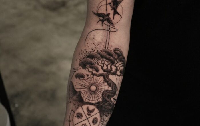 Black and grey forearm tattoo combining geometric, illustrative, and fine-line styles with birds, a bonsai tree, and dotwork elements