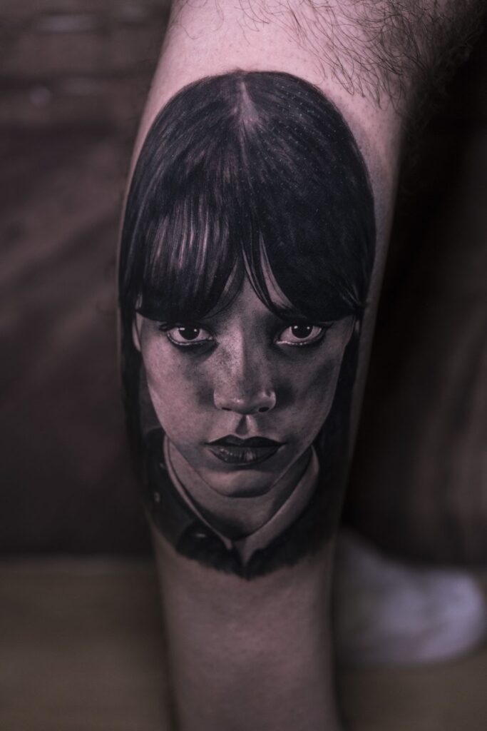 Black and grey realism tattoo of Wednesday Addams from the “Wednesday” television series