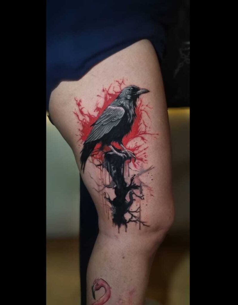 A Trash Polk-inspired thigh tattoo of a black crow perched on a branch, surrounded by bold red watercolor-style splashes.
