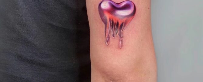 A small, colorful tattoo of a melting heart with glossy, metallic shading on the back of the arm.