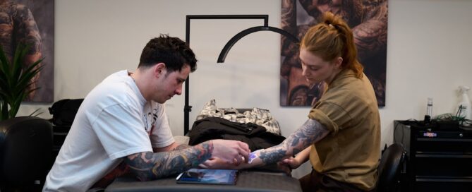 tattoo artist consulting with a client while reviewing the stencil placement on their forearm