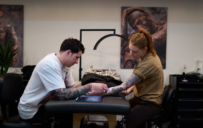 tattoo artist consulting with a client while reviewing the stencil placement on their forearm