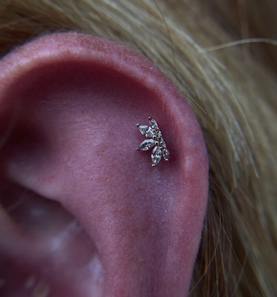 Close up of a top cartilage piercing with a diamond, half lotus earring