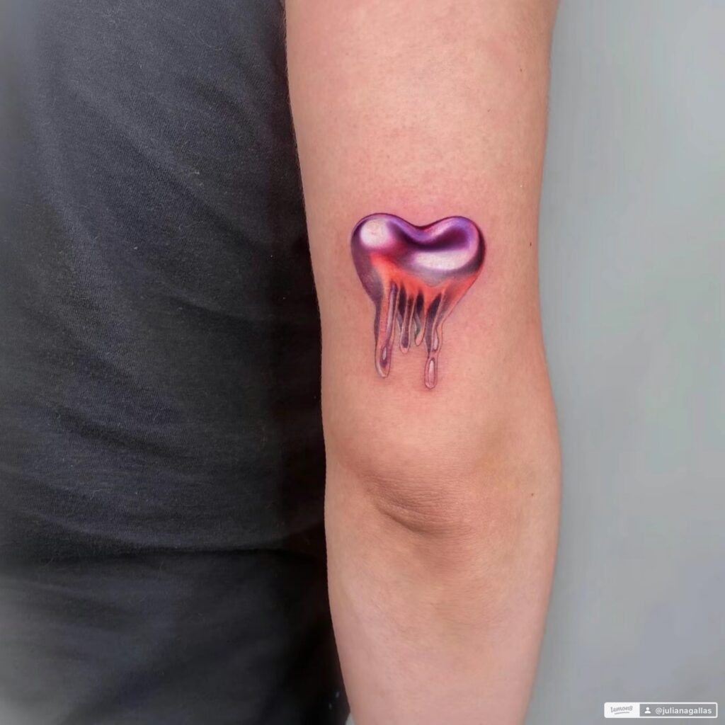 A chrome effect heart on the back of an arm, above the elbow