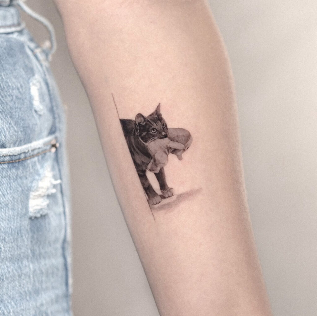 a micro realism tattoo of a cat holding a kitty with shadow effect on a forearm