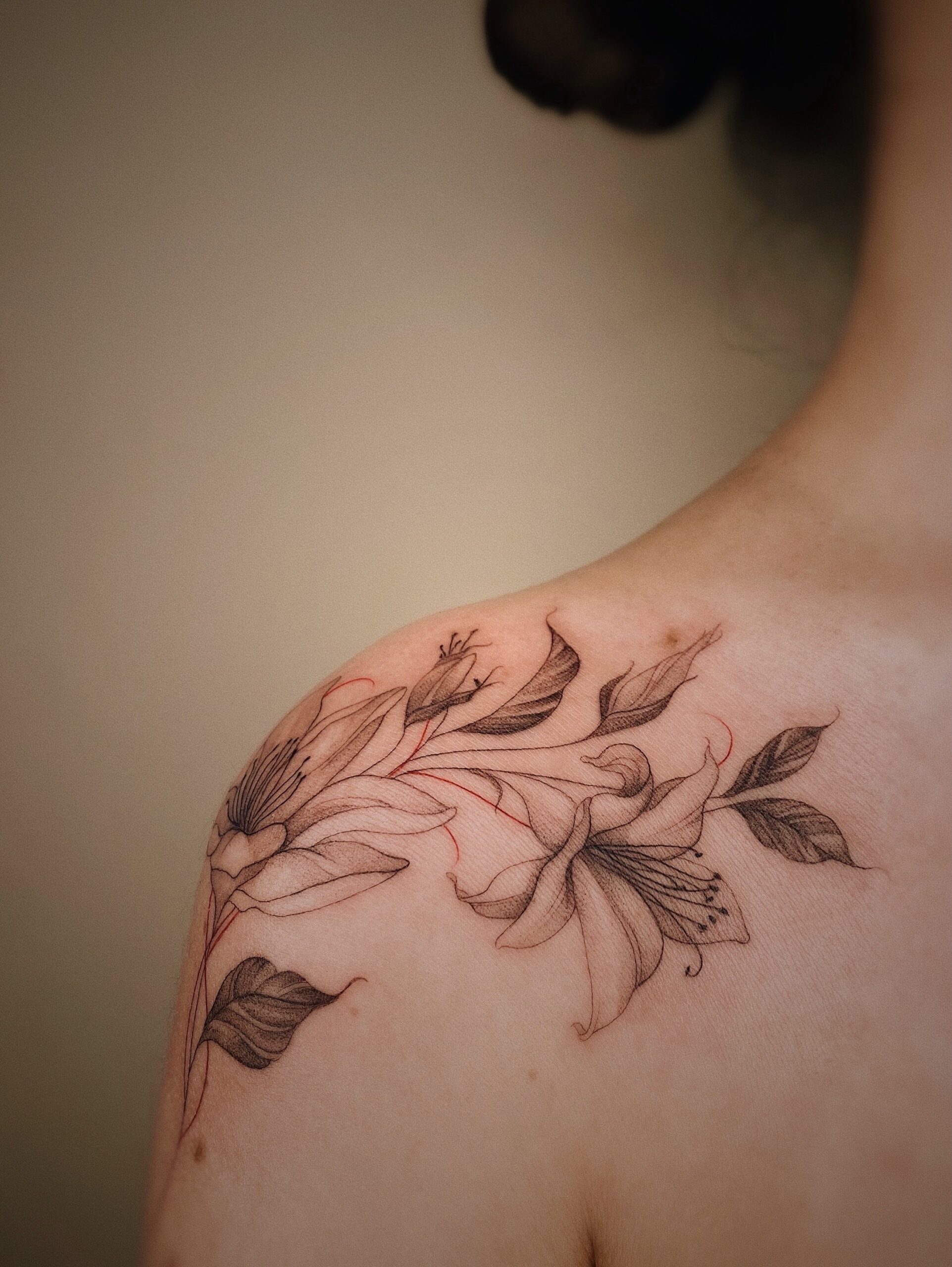 delicate, fine line floral tattoo across a female shoulders.