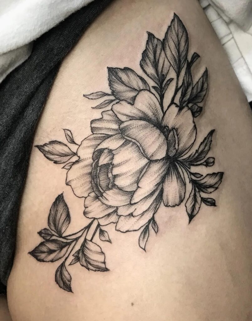 A black and grey fine-line tattoo of a large peony flower with detailed leaves and small buds on a person's hip or upper thigh.